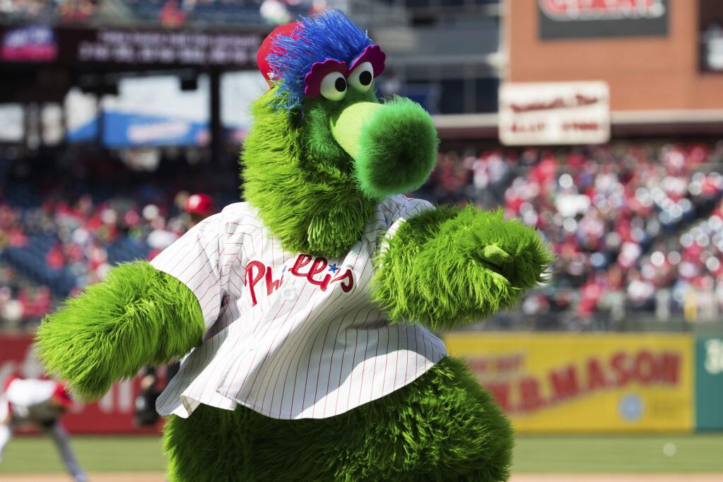 In this April 5, 2018 photo, The Phillie Phanatic reacts prior to the first inning of a baseball game against the Miami Marlins in Philadelphia. Kathy McVay says she was at Monday, June 18, Phillies game when the team's mascot, the Phillie Phanatic, rolled out his hot dog launcher. McVay was sitting near home plate and all of a sudden she says a hot dog wrapped in duct tape struck her in the face. She left the game to get checked out at a hospital, and she says she has a small hematoma. The Phillies apologized to McVay Tuesday and the team has offered her tickets to any game. (AP Photo/Chris Szagola)