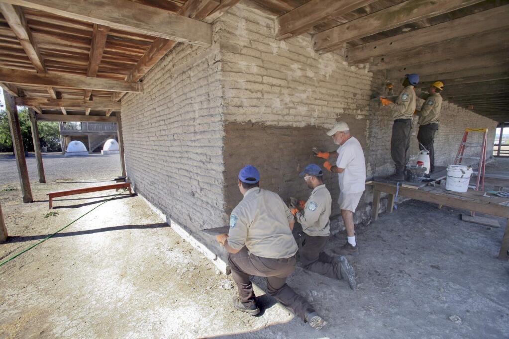 Members of the California Conservation Corps work with Architect Gil Sanchez, in white t-shirt as they put a layer of modified mud on an outside wall of the Petaluma Old Adobe in Petaluma on Tuesday, September 23, 2014. Corps members are from left, Anthony Hernandez, Peter Ravlin, Andrew Scott, and Tyler Wilcox. (SCOTT MANCHESTER/ARGUS-COURIER STAFF)