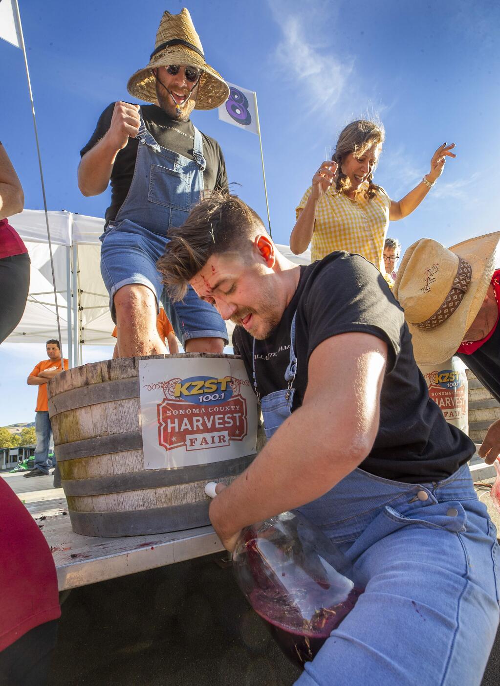 Dan Dykeman keeps his feet churning while Evan Strandberg uses an arm to push juice into a jug at the 45th annual Sonoma County Harvest Fair on Friday. The pair won a competition in Oregon and won the opportunity to compete in the World Championship Grape Stomp. (photo by John Burgess/The Press Democrat)