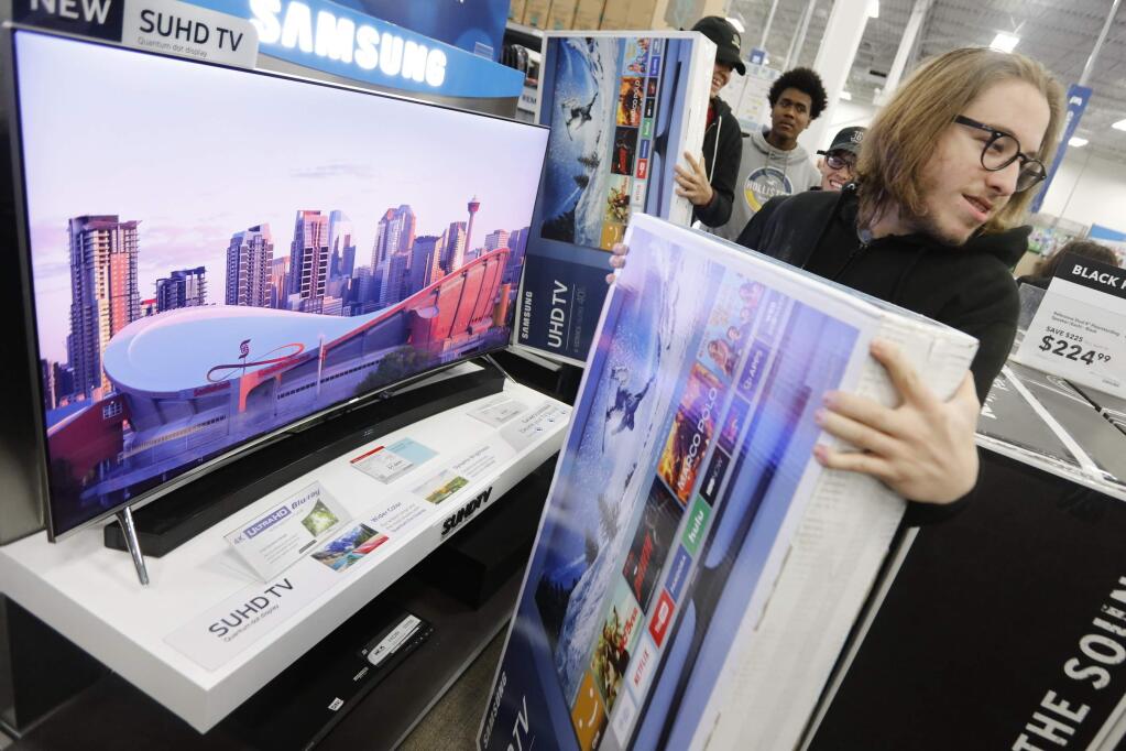 Joseph Rebelo grabs the television he waited in line for as he and fellow shoppers look for the best deals at Best Buy on Black Friday, in Dartmouth, Mass., Nov. 25, 2016. Stores open their doors Friday for what is still one of the busiest days of the year, even as the start of the holiday season edges ever earlier. (Peter Pereira/Standard Time/SCMGs via AP)