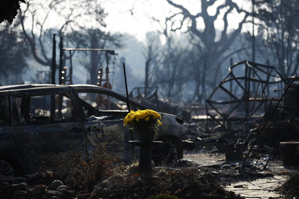 A bouquet of fresh flowers are placed, Sunday, Oct. 15, 2017, in the Coffey Park neighborhood in Santa Rosa, Calif., that was devastated by a wildfire. A state fire spokesman says it appears firefighters are making good progress on deadly wildfires that started a week earlier, devastating wine country and other parts of rural Northern California. (AP Photo/Jae C. Hong)