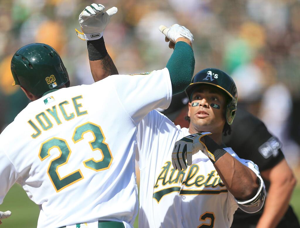 Khris Davis is congratulated at home by Matt Joyce after Davis clubbed a three-run home run during the fifth inning against the Angels, Thursday March 29, 2018. (Kent Porter / The Press Democrat) 2018