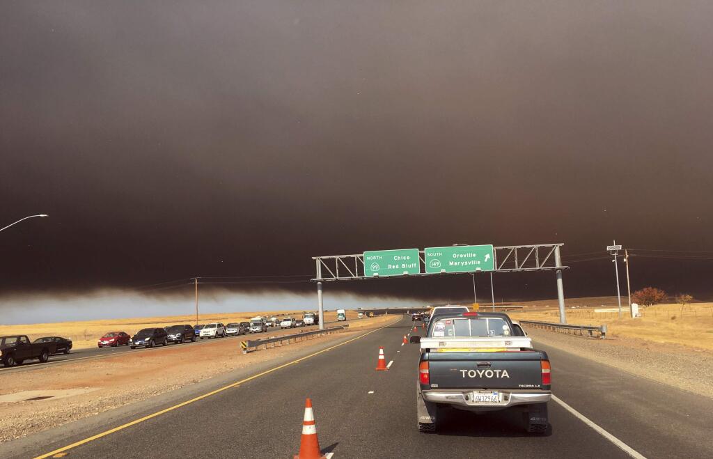 Smoke from the Camp Fire, burning in the Feather River Canyon near Paradise, Calif., darkens the sky as seen from Highway 99 near Marysville, Calif., Thursday, Nov. 8, 2018. (AP Photo/Don Thompson)