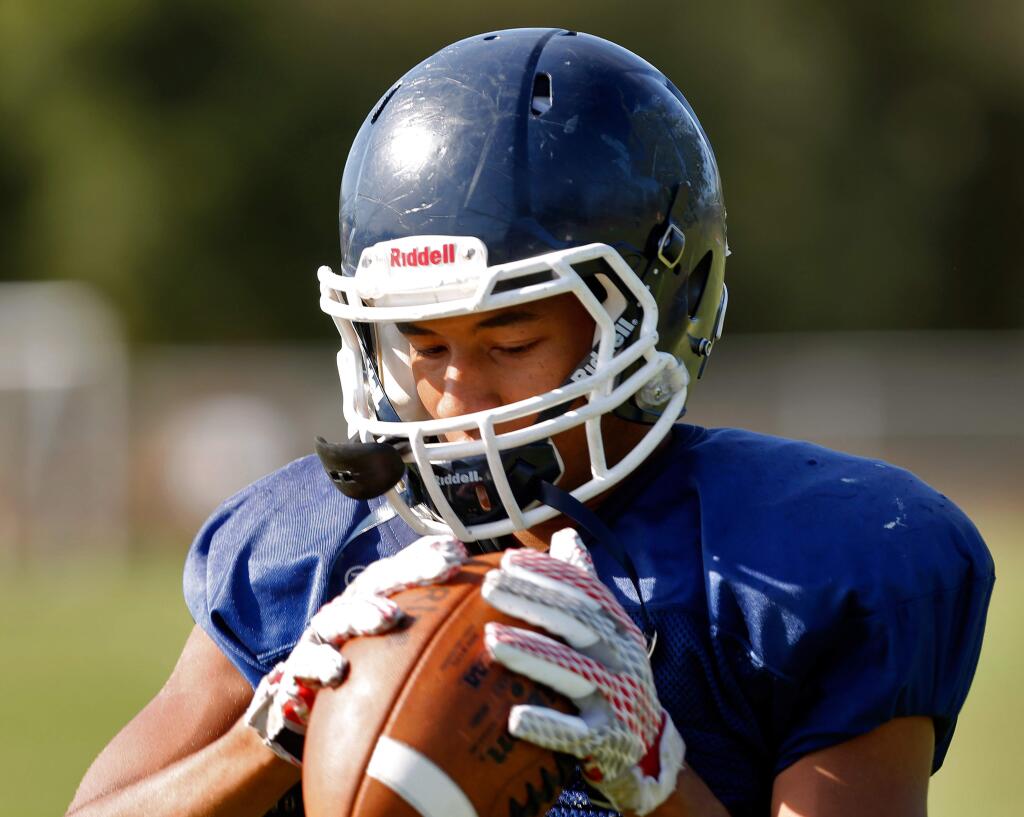 Chris Taylor-Yamanoha pulls in the ball during varsity football practice at Rancho Cotate high school in Rohnert Park, California on Tuesday, September 1, 2015.