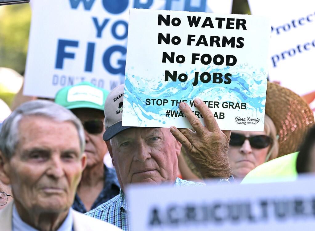 FILE - In this Aug. 20, 2018 file photo, California farmers rally at the Capitol to protest a proposal by state water officials to increase water flows for the lower San Joaquin River to protect fish, at the Capitol in Sacramento, Calif. A state water board is scheduled to vote Wednesday, Dec. 12, 2018, on a contentious proposal to boost flows through a Central California river and its tributaries, increasing habitat for salmon but delivering less water for cities and farmers. State officials say water users along the Tuolumne River have agreed to voluntary concessions that would improve salmon habitat instead of the mandated increase in water flows. (AP Photo/Rich Pedroncelli, File)