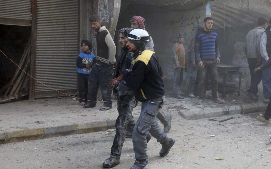 This photo provided by the Syrian Civil Defense White Helmets, which has been authenticated based on its contents and other AP reporting, shows a civil defense worker helping a wounded man after airstrikes hit a rebel-held suburb near Damascus, Syria, Thursday, Feb. 8, 2018. Syrian rescue workers and activists say the death toll from ongoing government strikes on the opposition-held region near the capital Damascus has risen to at least 35. (Syrian Civil Defense White Helmets via AP)