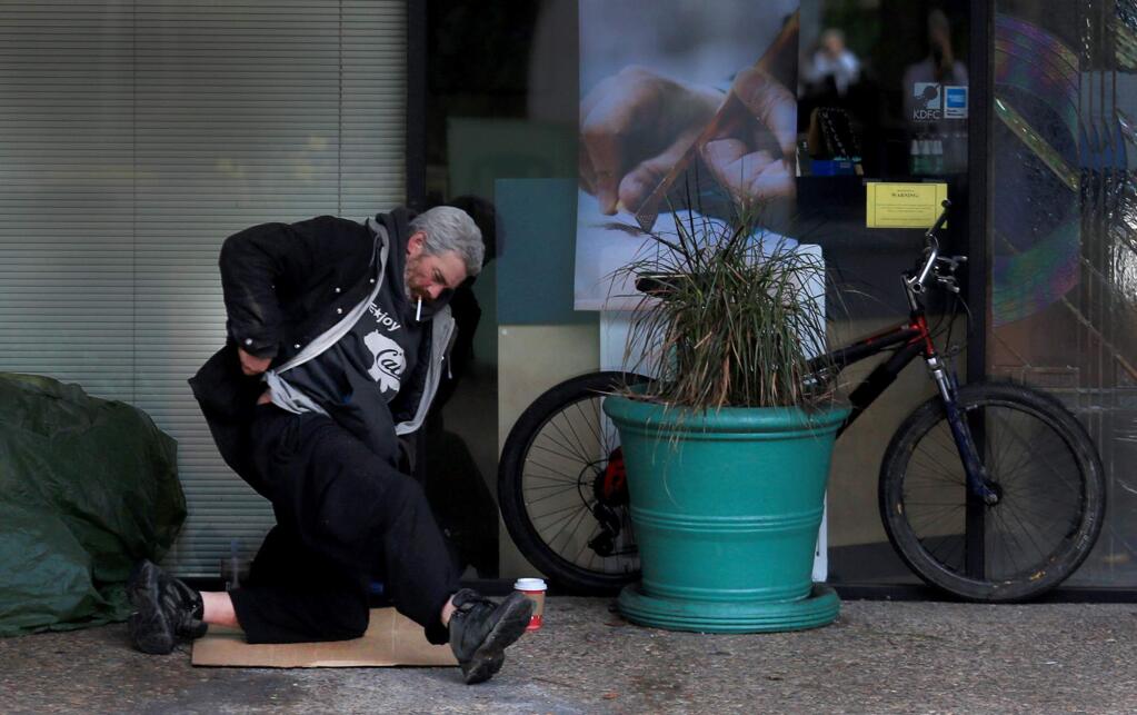 A man puts his belongings together after an overnight stay in a business alcove along Fourth Street in Santa Rosa on Wednesday Nov. 30, 2016. (KENT PORTER/ PD)