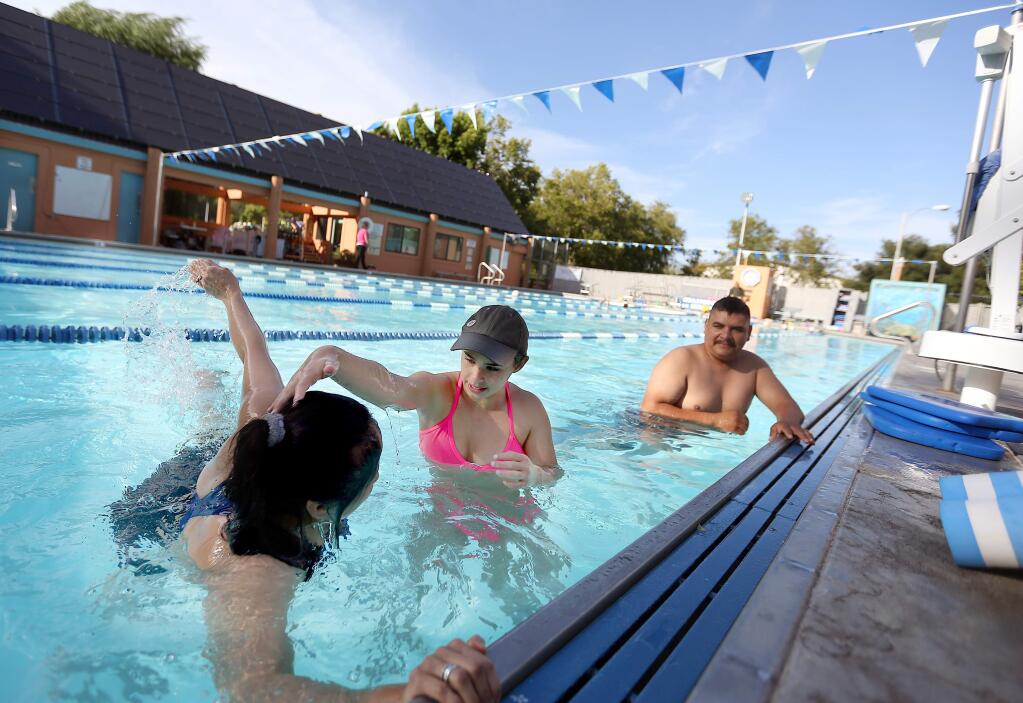 Sarah Poplack, center, a swimming instructor, works with Dulia Salmeron, left, and Eric Valdovinos, right, during swim lessons held at Ives Pool in Sebastopol, Wednesday, July 8, 2015. (CRISTA JEREMIASON / The Press Democrat)