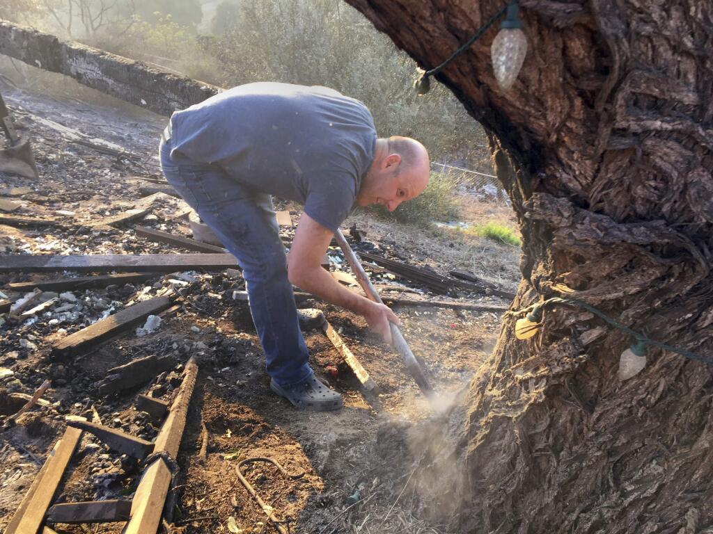 Resident Brent Rosenzweig uses water to put out a smoldering tree in his backyard, as he worries about losing his family home in the second round of weather coming in Ventura, Calif., Wednesday, Dec.6, 2017. Wind-driven fires have raced through California communities for the second time in two months, leaving hundreds of homes feared lost and uprooted tens of thousands of people. The most damaging fire is in Ventura County northwest of Los Angeles, where more than 100 square miles (259 sq. kilometers) and numerous homes have burned. (AP Photo/Amanda Lee Myers)