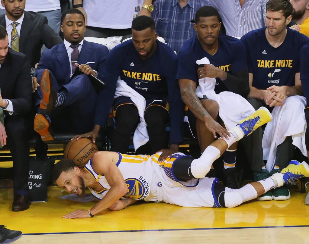 Golden State Warriors guard Stephen Curry lands in front of the Utah Jazz bench while going after a loose ball during Game 2 of the Western Conference semifinal round in Oakland on Thursday, May 4, 2017. (Christopher Chung / The Press Democrat)