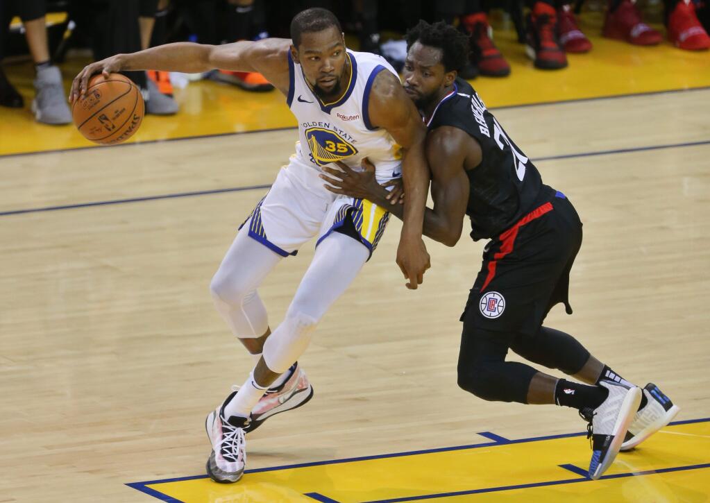 Golden State Warriors forward Kevin Durant backs down toward the basket against Los Angeles Clippers guard Patrick Beverley during a playoff game in Oakland on Saturday, April 13, 2019. (Christopher Chung / The Press Democrat)