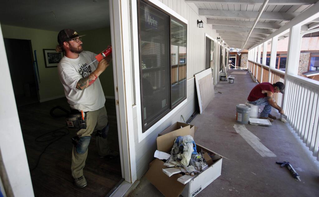 Tyler Black, left, caulks the door frame as Mike Wilkinson, right, paints the railings in preparation for the re-opening of Hoberg's Resort & Spa in Cobb, Wednesday, Aug. 13, 2014. (Crista Jeremiason / The Press Democrat)