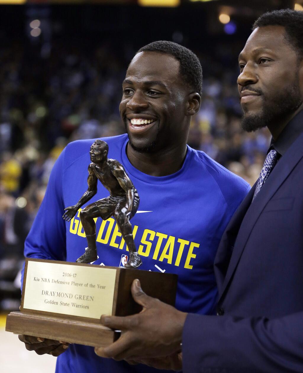 The Golden State Warriors' Draymond Green, left, receives the NBA defensive player of the year award from Ben Wallace prior to a a preseason game against the Denver Nuggets Saturday, Sept. 30, 2017, in Oakland. (AP Photo/Ben Margot)