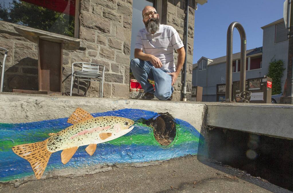 City of Santa Rosa senior environmental specialist Nick Sudano kneels next to a storm drain painted by the city to remind people that the drains ultimately flow into our creeks and ocean. (John Burgess/The Press Democrat)