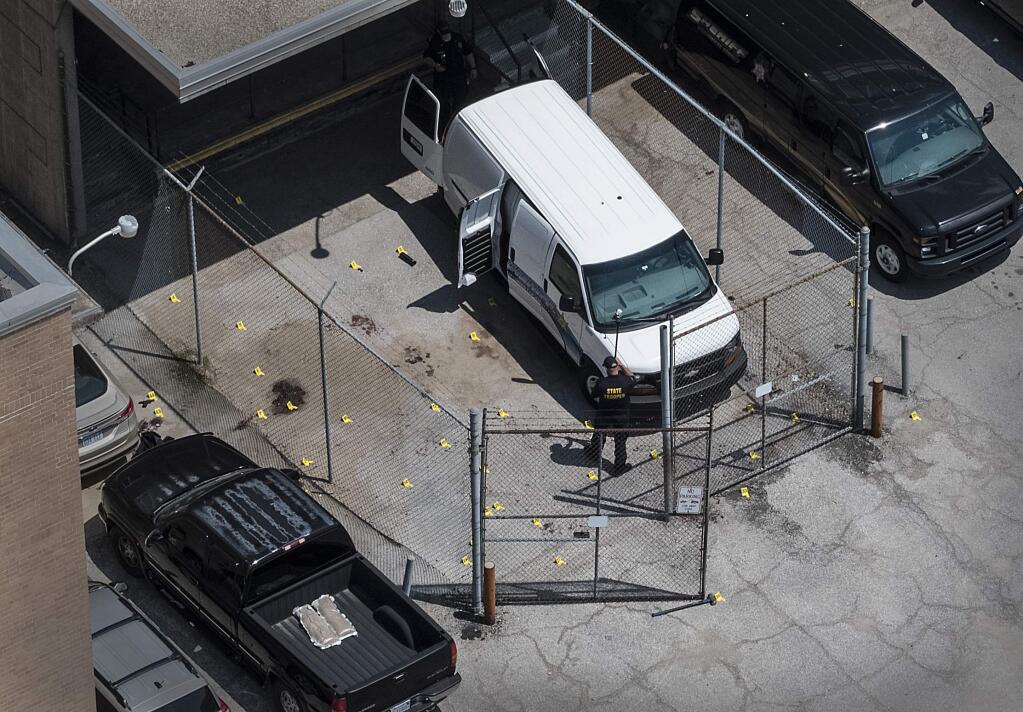 Evidence markers dot the pavement just outside the Wyandotte County courthouse, Friday, June 16, 2018, in Kansas City, Kan. Authorities say one sheriff's deputy is dead and another is critically wounded after they were overcome by an inmate while driving a transport vehicle near the courthouse./The Kansas City Star via AP)