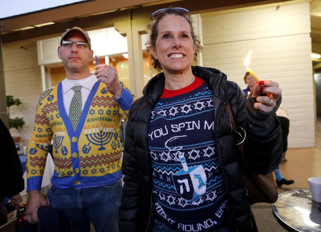 Yvonne Cobert and her husband Jerome hold candles and listen to live music performed by the band Ilturim during the Grand Chanukah Festival at Montgomery Village on Sunday, Dec. 17, 2017 in Santa Rosa, California. (BETH SCHLANKER/The Press Democrat)