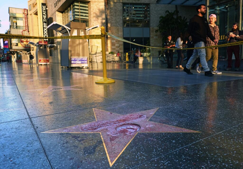 Pedestrians walk past a cordoned off area surrounding the vandalized star for Republican presidential candidate Donald Trump on the Hollywood Walk of Fame, Wednesday, Oct. 26,2016, in Los Angeles. Det. Meghan Aguilar said investigators were called to the scene before dawn Wednesday following reports that Trump's star was destroyed by blows from a hammer. (AP Photo/Richard Vogel)