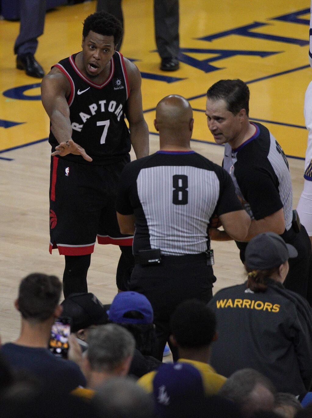 Toronto Raptors guard Kyle Lowry (7) gestures next to referees Marc Davis (8) and referee Kane Fitzgerald near the front row of fans during the second half of Game 3 of basketball's NBA Finals between the Golden State Warriors and the Raptors in Oakland, Calif., Wednesday, June 5, 2019. A fan seated courtside for Game 3 of the NBA Finals was ejected after shoving Lowry when the Raptors star crashed into a row of seats while trying to save a ball from going out of bounds on Wednesday night. (AP Photo/Tony Avelar)