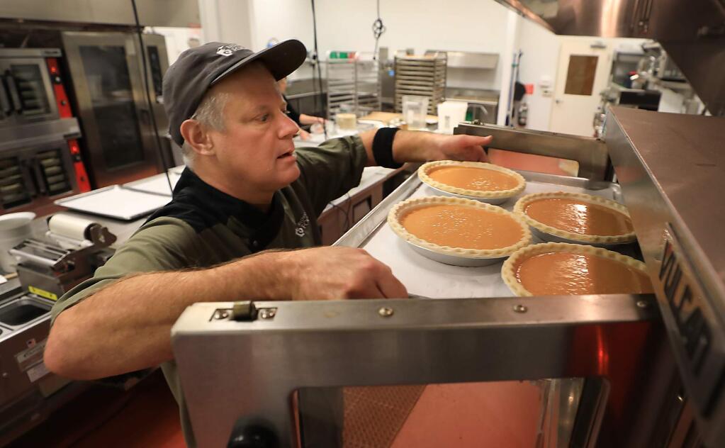 Redwood Empire Food Bank chef Don Nolan slides pumpkin pie in to an oven, in which the pies were made by Kati Hilario, who begins another Thanksgiving of donating the profits to the Redwood Empire Food Bank, Tuesday Nov. 20, 2018 in Santa Rosa. (Kent Porter / The Press Democrat) 2018