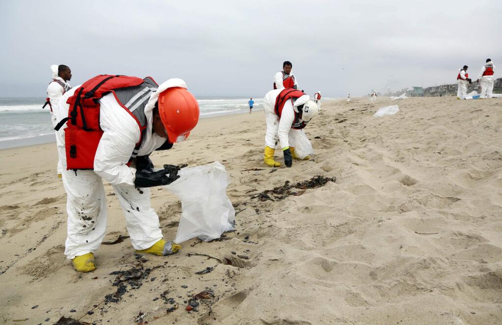 A crew cleans up a beach after balls of tar washed ashore in Manhattan Beach, Calif. on Thursday, May 28, 2015. Popular beaches along nearly 7 miles of Los Angeles-area coastline are off-limits to surfing and swimming after balls of tar washed ashore. The beaches along south Santa Monica Bay appeared virtually free of oil Thursday morning after an overnight cleanup, but officials aren't sure if more tar will show up. (AP Photo/Nick Ut)