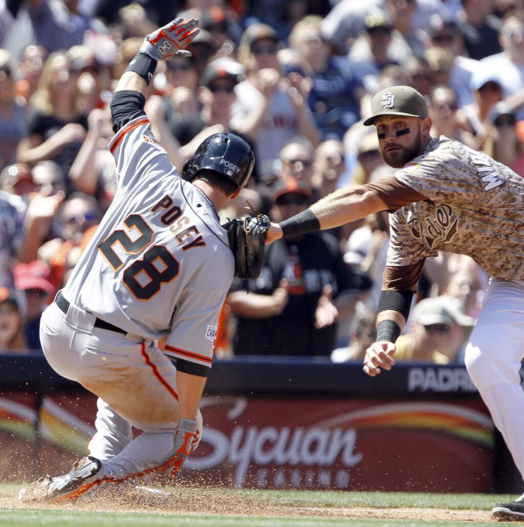 San Diego Padres third baseman Will Middlebrooks, right, applies the tag but San Francisco Giantsí Buster Posey (28) slides safely into third from first on a run-scoring single by Brandon Belt during the third inning of a baseball game in San Diego, Calif., Sunday, April 12, 2015. (AP Photo/Alex Gallardo)