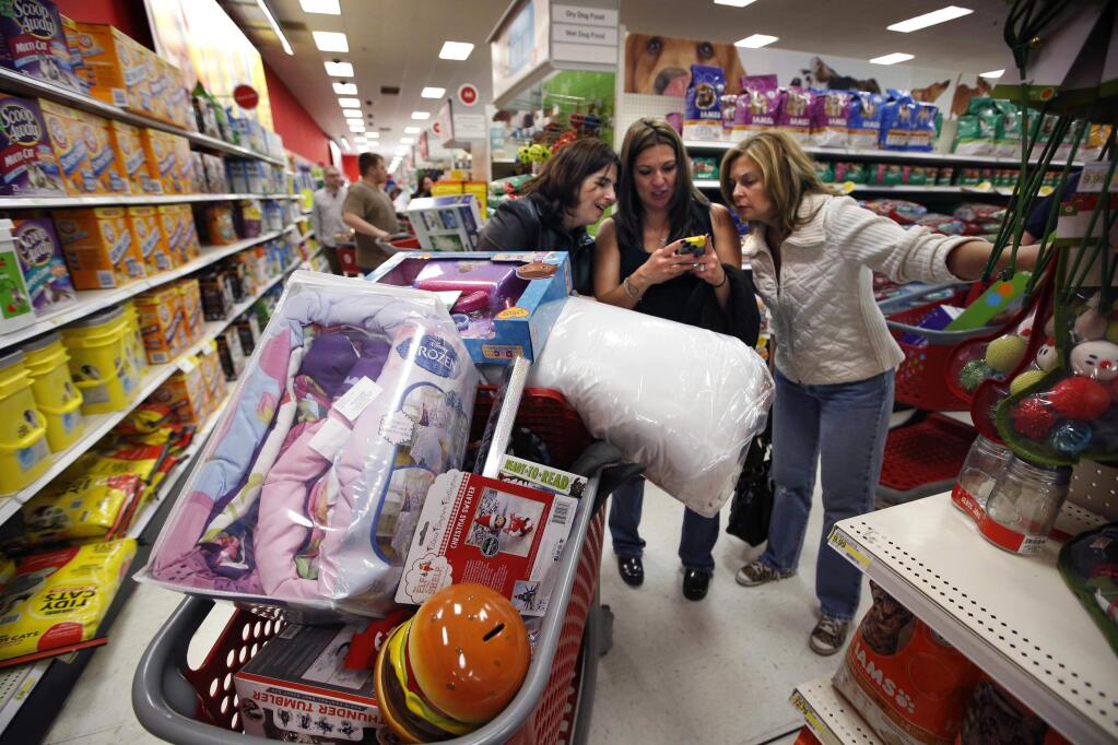 FILE - In this Nov. 28, 2014, file photo, Target shoppers Kelly Foley, left, Debbie Winslow, center, and Ann Rich use a smartphone to look at a competitor's prices while shopping shortly after midnight on Black Friday, in South Portland, Maine. Stores have been pushing deals on holiday merchandise throughout November, but they'll be stepping it up for the official holiday kickoff, the busiest days of the year. 2017 has been a tough year in retail, with many store closures and some bankruptcies. But with unemployment low, stores are hoping customers are in a mood to shop. (AP Photo/Robert F. Bukaty, File)