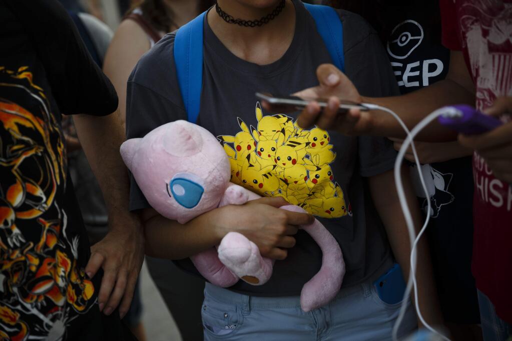 Spanish fans play the highly addictive Pokemon Go game during a gathering in central Madrid, Spain, Thursday, July 28, 2016, to play the computer game. In the game players try to capture, battle, and train virtual creatures in their real world locations using the GPS and camera on their smart devices. (AP Photo/Daniel Ochoa de Olza)