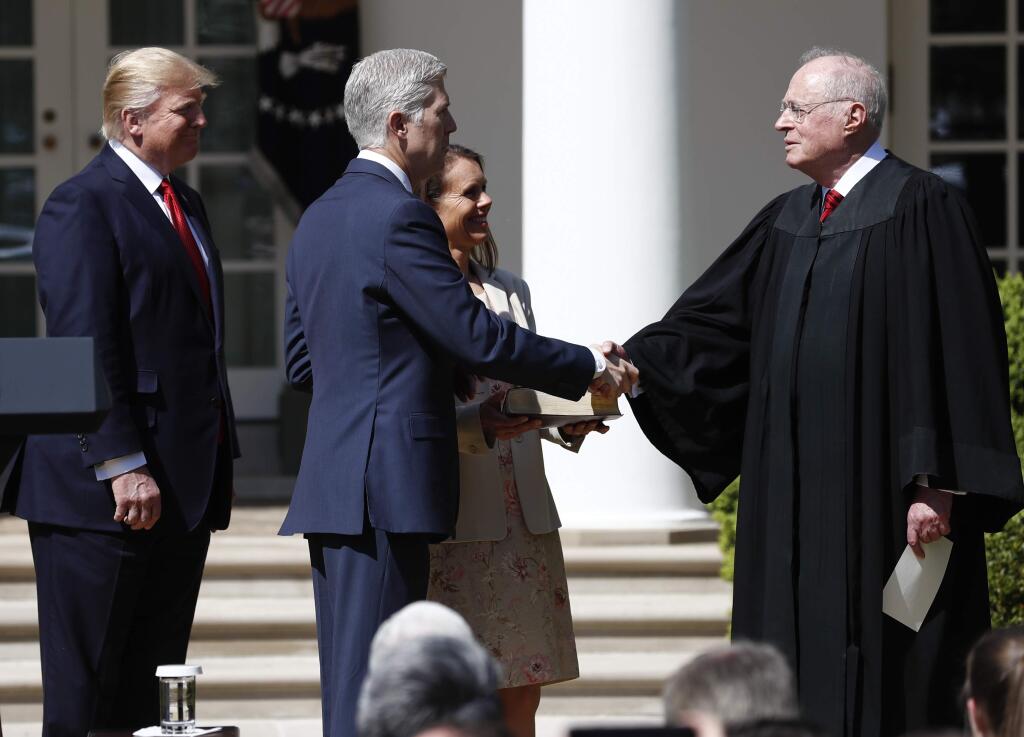 President Donald Trump, left, Supreme Court Justice Anthony Kennedy, right, participate in a public swearing-in ceremony for Justice Neil Gorsuch, second from left, in the Rose Garden of the White House White House in Washington, Monday, April 10, 2017. Holding the bible, is Gorsuch's wife Marie Louise Gorsuch. (AP Photo/Carolyn Kaster)