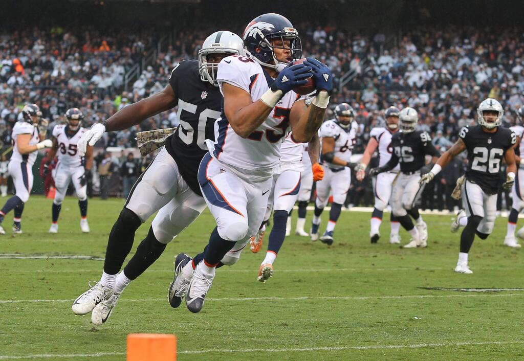 Denver Broncos running back Devontae Booker pulls in a pass in front of Oakland Raiders linebacker Nicholas Morrow during their game in Oakland on Sunday, November 26, 2017. The Raiders defeated the Broncos 21-14.(Christopher Chung/ The Press Democrat)