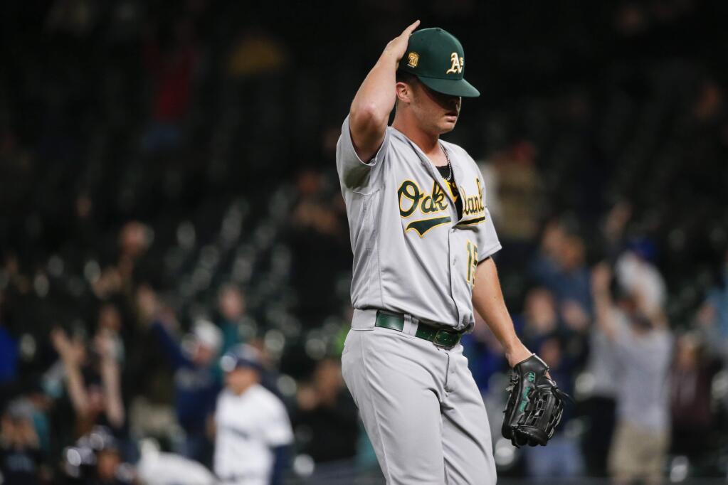 Oakland Athletics relief pitcher Emilio Pagan adjusts his hat after giving up a walk-off two-run home run to Seattle Mariners' Chris Herrmann during the eleventh inning of a baseball game Tuesday, Sept. 25, 2018, in Seattle. Seattle won 10-8. (AP Photo/Jennifer Buchanan)
