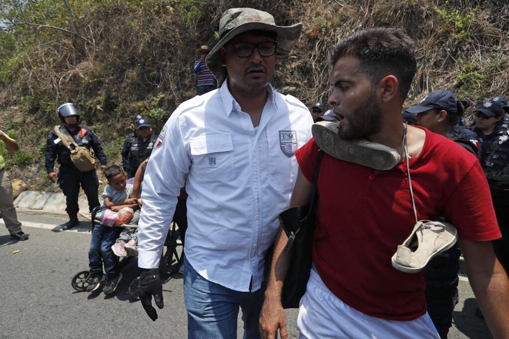 A Central American migrant, right, is taken into custody by a Mexican Federal Police agent on the highway to Pijijiapan, Mexico, Monday, April 22, 2019. Mexican police and immigration agents detained hundreds of Central American migrants Monday in the largest single raid on a migrant caravan since the groups started moving through Mexico last year. (AP Photo/Moises Castillo)