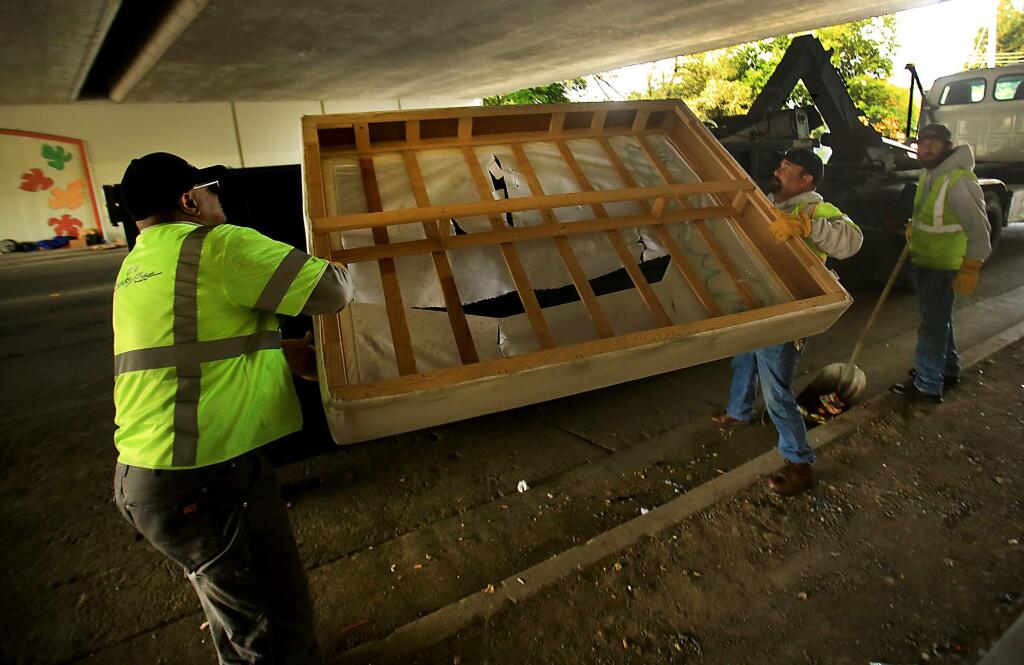 Santa Rosa city workers clean up debris from a homeless encampment at the Sixth Street under crossing in Santa Rosa on Wednesday, April 5, 2017. (KENT PORTER/ PD FILE)