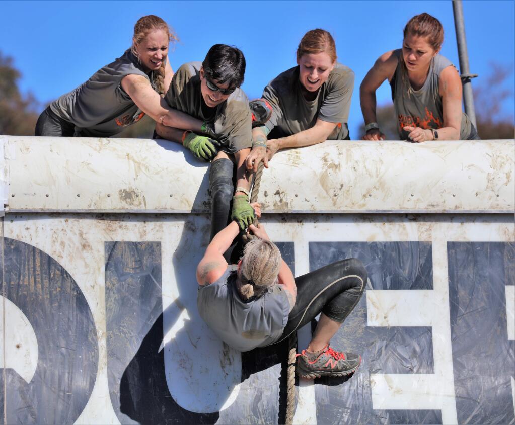 Team members assist a participant over a 14 foot wall at the Tough Mudder 5k and Tough Mudder 10k at Sonoma Raceway in Sonoma California, Saturday, Oct. 5, 2019. (WILL BUCQUOY/FOR THE PRESS DEMOCRAT)