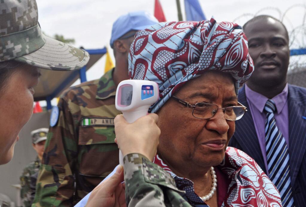 Liberian President Ellen Johnson Sirleaf, center, temperature is taken by a Chinese soldier, left, before the opening of a new Ebola virus clinic sponsored by China, in Monrovia, Liberia, Tuesday, Nov. 25, 2014, Liberia got another 100 treatment beds in the fight against Ebola on Tuesday, as yet another Sierra Leonean doctor became infected with the disease sweeping West Africa. Liberian President Ellen Johnson Sirleaf toured the Ebola treatment center built by China, calling it first-class.(AP Photo/ Abbas Dulleh)