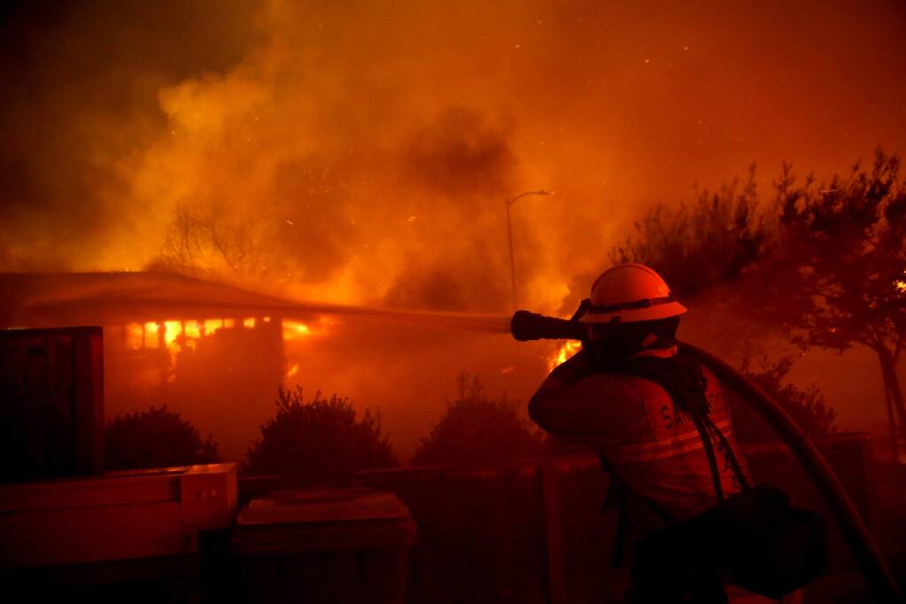 A Santa Rosa firefighter works to put out a house fire on Sansone Drive in Santa Rosa, on Monday, Oct. 9, 2017. (BETH SCHLANKER/ PD)