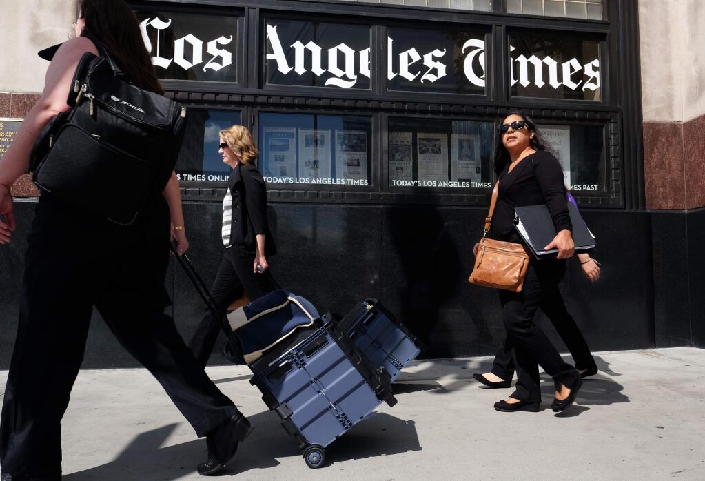 Pedestrians walk past the Los Angeles Times building in downtown Los Angeles on Monday, Oct. 5, 2015. In a memo that was obtained by The Associated Press on Monday, Tribune Publishing, the owner of the Los Angeles Times, Chicago Tribune and other newspapers, says it is offering buyouts to employees. (AP Photo/Richard Vogel)