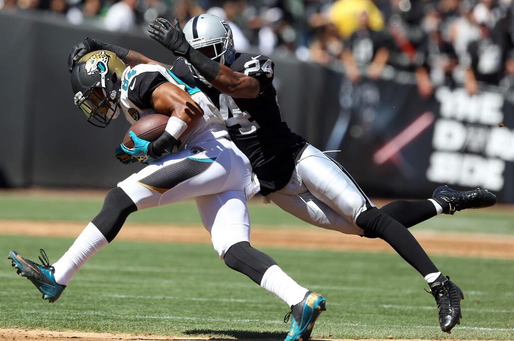 Oakland Raiders safety Charles Woodson tackles Jacksonville Jaguars wide receiver Cecil Shorts during their game in Oakland, on Sunday, September 15, 2013. (Christopher Chung/ The Press Democrat)