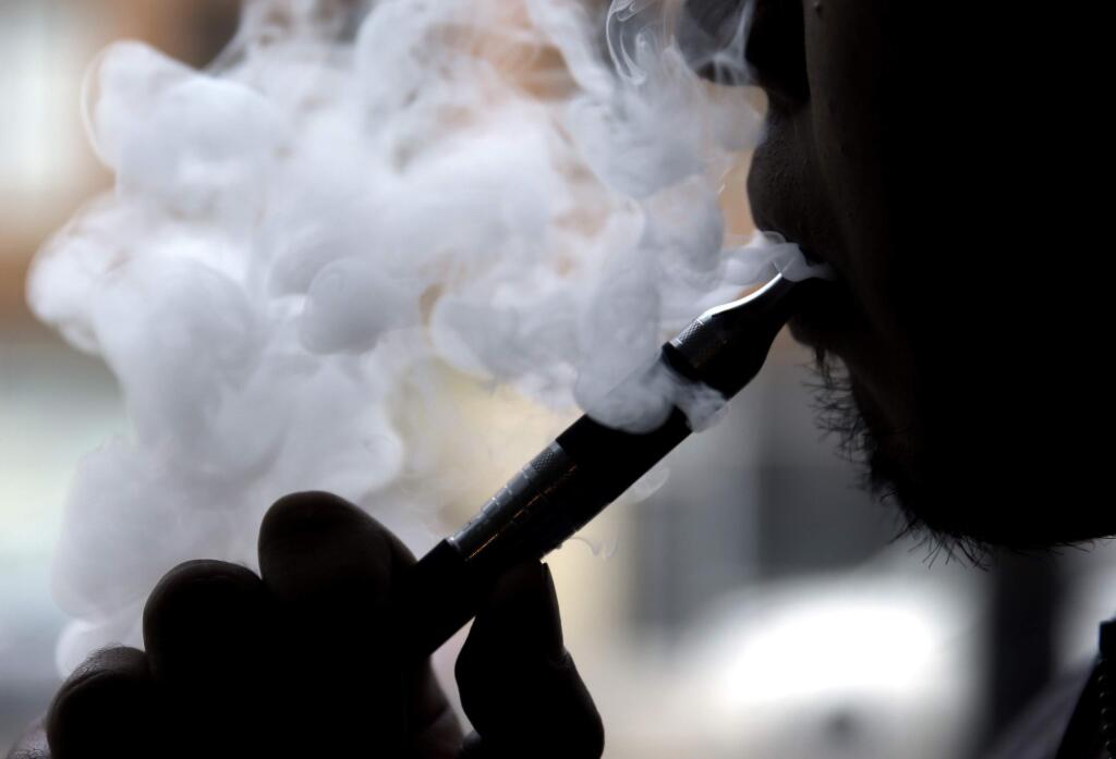 FILE - In this April 23, 2014 file photo, a man smokes an electronic cigarette in Chicago. (AP Photo/Nam Y. Huh, File)