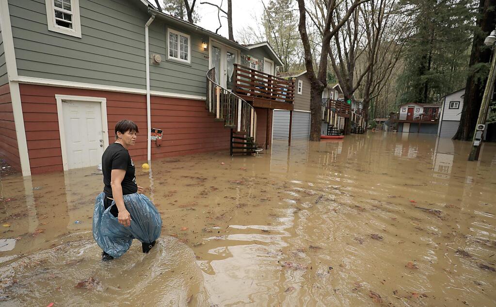 Chris Tipton looks for floating toys and personal belongings after Armstrong Creek flooded earlier this month in Guerneville. (KENT PORTER / The Press Democrat)