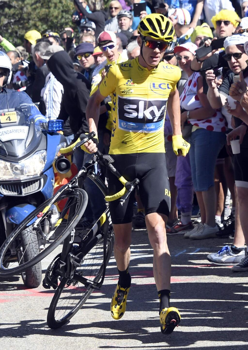 Britain's Chris Froome, wearing the overall leader's yellow jersey, runs with his bike after he crashed at the end of the twelfth stage of the Tour de France cycling race with start in Montpellier and finish six kilometers (3.7 miles) before the Mont Ventoux, France, Thursday, July 14, 2016. The wind, combined with a temperature just above the freezing level on top of the 'Giant of Provence,' forced organizers to move the finish line six kilometers (3.7 miles) down the road to the Chalet Reynard. (Bernard Papon/ Pool Photo via AP)