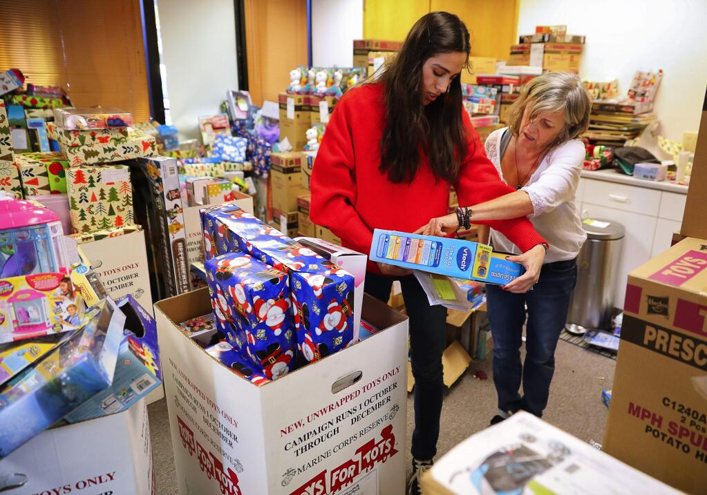 Volunteers Raquel Palmerin, left, and Annamarie Sarto gather gifts for a family for the Volunteer Center of Sonoma County's Secret Santa program, in Santa Rosa on Wednesday, December 20, 2017. (Christopher Chung/ The Press Democrat)