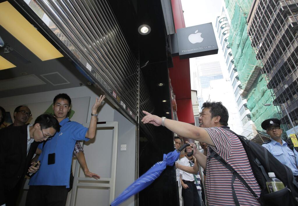 A man shouts to an Apple premium reseller store after failed to buy the new Apple iPhone 6 and 6 Plus devices, in Hong Kong Friday morning, Sept. 19, 2014. The iPhone 6 and 6 Plus were released on Friday in Hong Kong. (AP Photo/Vincent Yu)