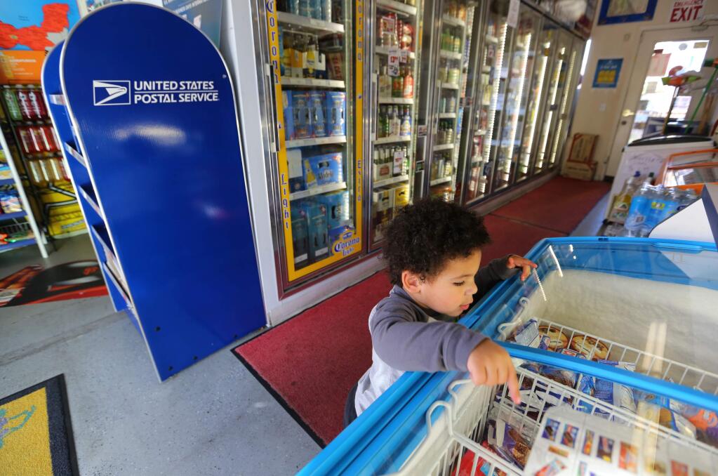 Charles Dortch IV, 23 months, checks out the ice cream freezer at La Famiglia Deli on Sebastopol Road, Tuesday, October 28, 2014. There is a new postal program called 'Village Post Office,' and one of their locations is inside La Famiglia Deli. (Crista Jeremiason / The Press Democrat)