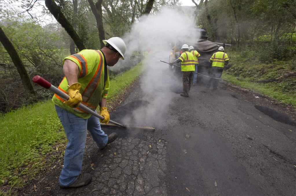 A county crew fill potholes on Enterprise Road on Monday, March 6. (Photo by Robbi Pengelly/Index-Tribune)
