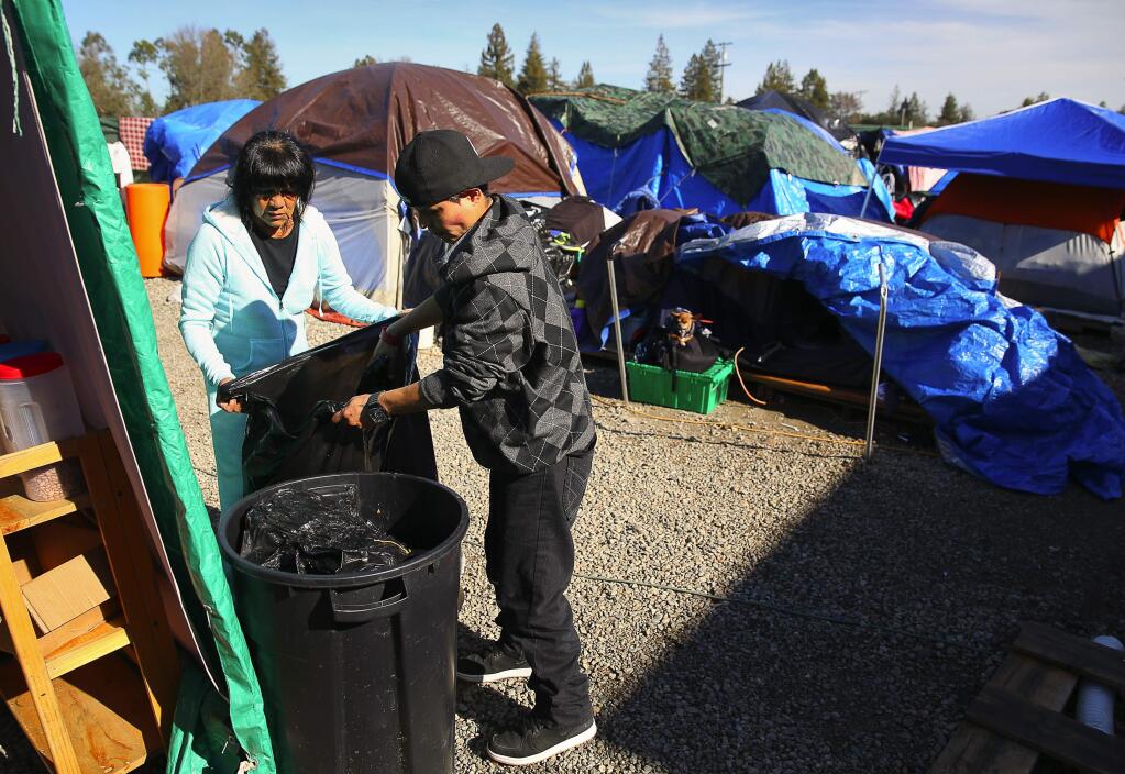 Tess Ala, left, and Rena Patterson empty a garbage can at the Roseland Village homeless camp, known as Camp Michela, in Santa Rosa, on Monday, Jan. 30, 2017. (Christopher Chung/ The Press Democrat)