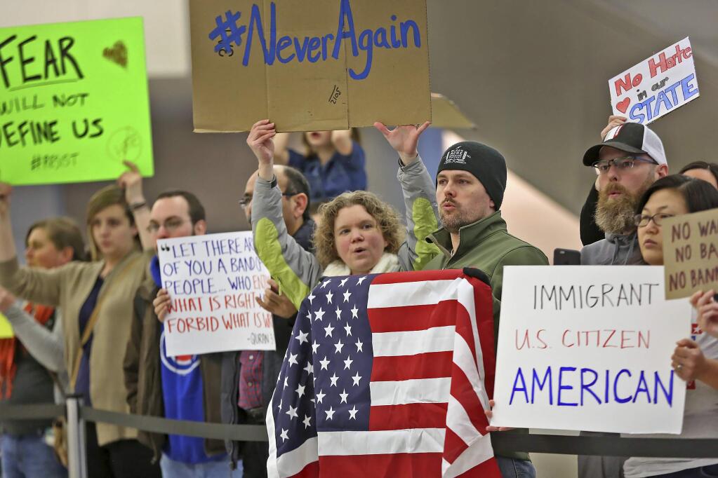 People chant slogans at the Indianapolis International Airport, Sunday, Jan. 29, 2017, during a protest against President Donald Trump's executive order temporarily suspending all immigration for citizens of seven majority Muslim countries for 90 days. (Kelly Wilkinson/The Indianapolis Star via AP)