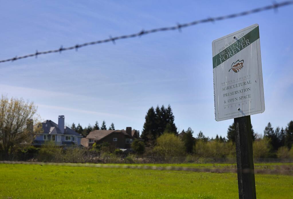 A Sonoma County Agricultural Preservation & Open Space District sign states that a plot of land north of Rohnert Park is protected forever. Residents are opposed to a proposal to put an incubator farm on the 45-acre parcel.(Christopher Chung/ The Press Democrat)