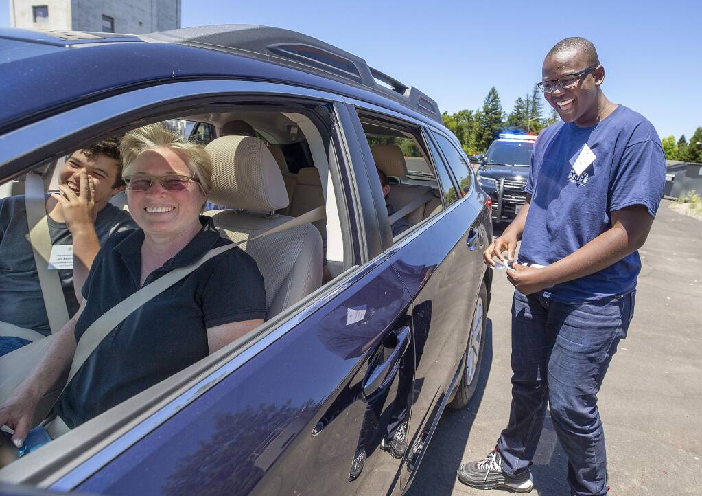 Justin Ikandu, 15, right, breaks character as he plays a traffic cop pulling over officer Christine Morrison, playing an elderly woman with the smell of marijuana coming from the car. Ikandu and other teams learned about being an officer during the Santa Rosa Police Department's Youth Community Police Experience program this week. (photo by John Burgess/The Press Democrat)