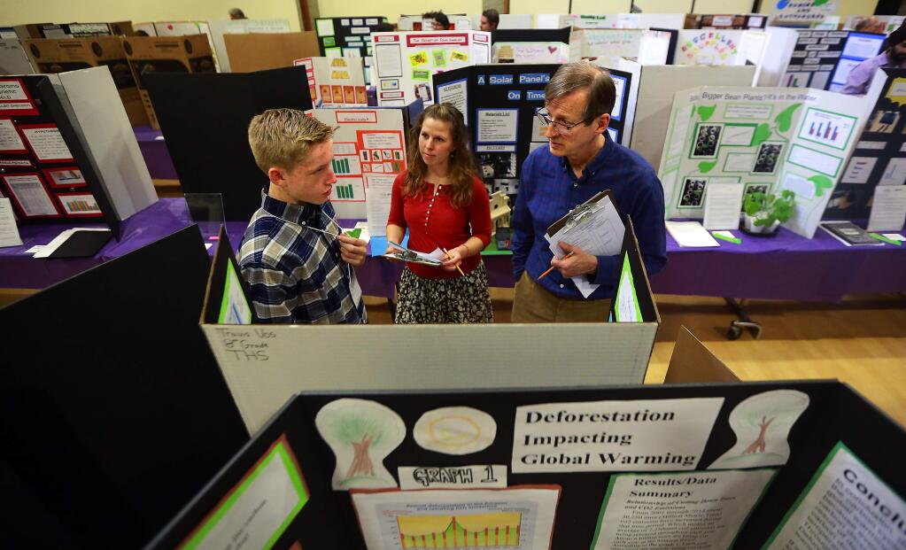 The Healdsburg School 8th grader Travis Vos discusses his project with judges Cody Ender, center, and Bob Lanier at the Synopsys-Sonoma County Science Fair at the Rohnert Park Community Center on Friday. (JOHN BURGESS / The Press Democrat)