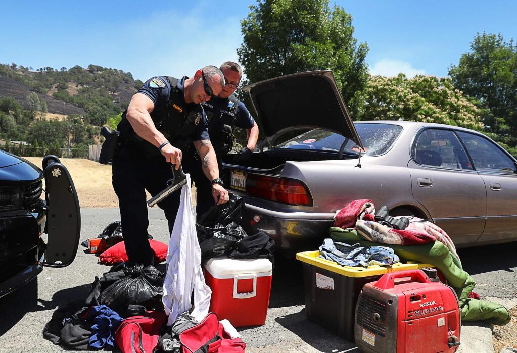 Clearlake Police Officer Mauricio Berreto, left, locates a firearm from a suspect's vehicle, while searching the car with Lakeport Police Officer Andrew Welter, in the evacuated area of Spring Valley Road, east of Clearlake Oaks, during the Pawnee fire on Monday, June 25, 2018. (CHRISTOPHER CHUNG/ PD)